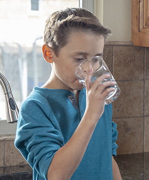 Un niño bebiendo un vaso de agua.